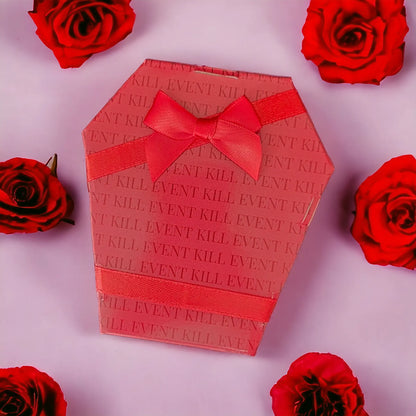 Boîte cadeau en forme de cercueil rouge Kill Event entourée de roses pour offrir une murder party
